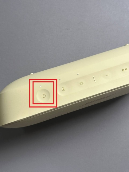 Menahan tombol daya pada speaker Bose SoundLink Flex II