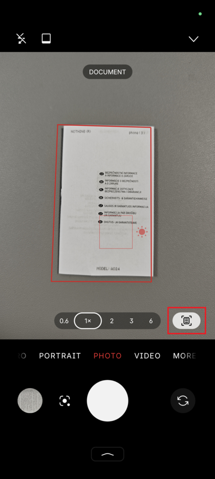 Eine Hand h&auml;lt ein Nothing Phone &uuml;ber einem flachen Dokument auf einem Schreibtisch, bereit zum Scannen.
